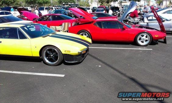 Yellow sports car with black stripes parked next to a red sports car with hood open
