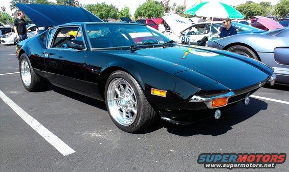 Black De Tomaso Pantera with hood up, parked at an outdoor event