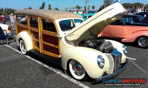 Cream woodie station wagon, hood open, showing engine. Whitewall tires