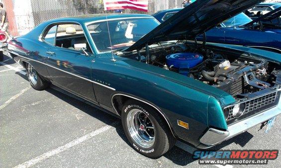 Teal coupe with hood open, showing engine and chrome wheels. "TORINO" badge visible
