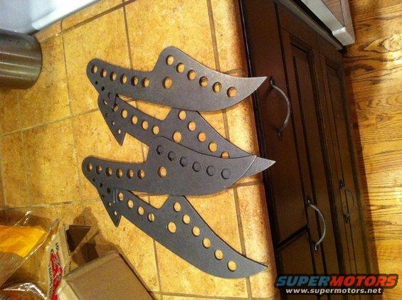 three metal automotive suspension components with many holes