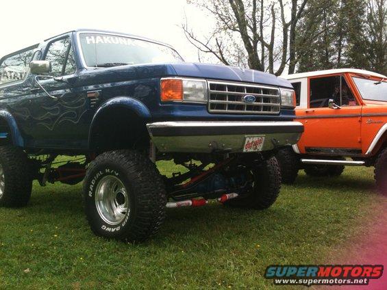 Blue 1992 Ford Bronco with flame decals, lifted, in a 3q-front view