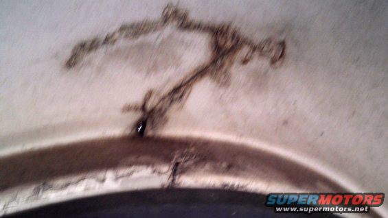 Close-up of rust and damage on an interior panel, possibly a wheel well