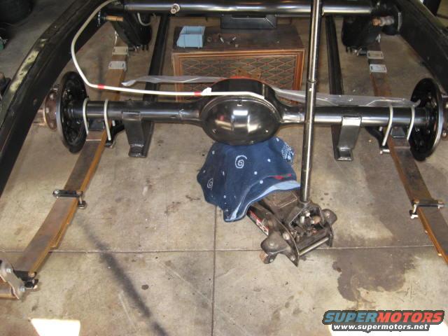 Rear axle assembly with leaf springs and brake drums, supported by a jack