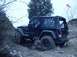 1992 Ford Bronco - Black Jeep Wrangler navigates a challenging off-road course on a cloudy day.