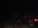 1992 Ford Bronco - A red pickup truck tows a trailer carrying another vehicle in the dark.