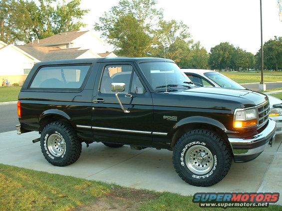 Black Ford Bronco parked on a driveway, another car is behind it