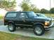 1995 Ford Bronco - This black Ford Bronco is parked in front of a house with a second vehicle behind it.