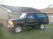 1995 Ford Bronco - This black 1995 Ford Bronco is parked on a grassy lawn in front of a house.