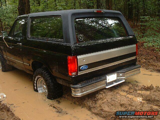 Black 1995 Ford Bronco stuck in mud, rear view