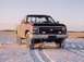 1988 Chevrolet Silverado 2500 - A pickup truck drives through a snowy landscape during golden hour.