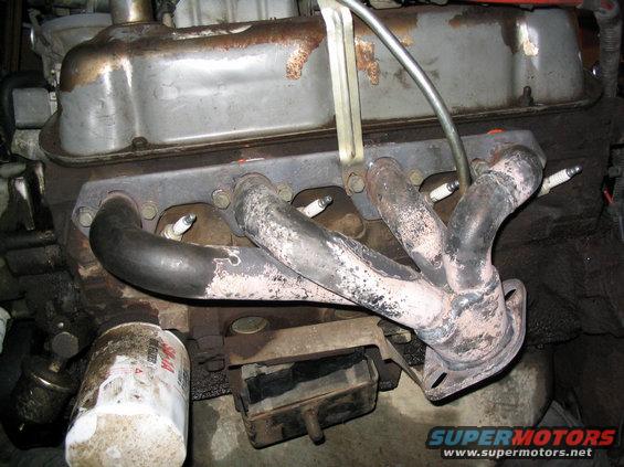 Engine exhaust manifold with spark plugs visible, oil filter on the left