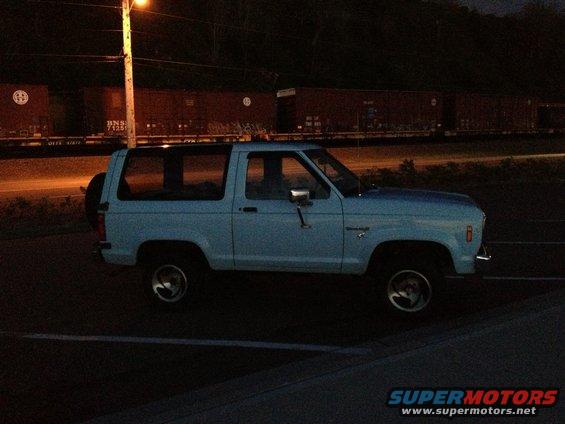 1985 Ford Bronco II parked at night with a train in the background