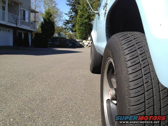 Light blue SUV side view, close-up on front tire and wheel well. Supermotors.net logo visible