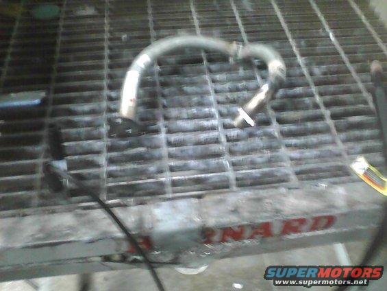 Metal exhaust pipe section on a metal grate, with red lettering visible on the grate's edge