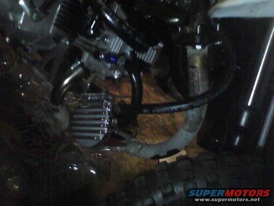 Close-up of motorcycle engine components including hoses and a finned metal part