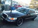 2000 Mercury Grand Marquis - A black Mercury Grand Marquis is parked in a residential driveway with a red pickup truck behind it.