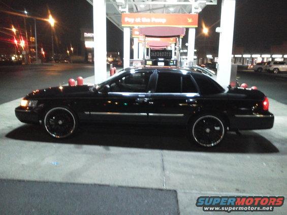 Black 2000 Mercury Grand Marquis sedan parked at a gas station at night