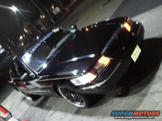 Black Mercury Grand Marquis parked at night. Sticker on windshield says 'GRAND MARQUIS'