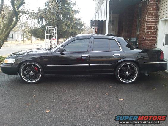 Black 2000 Mercury Grand Marquis with aftermarket wheels parked on asphalt
