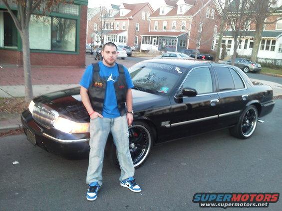 guy next to a black 2000 Mercury Grand Marquis with custom rims
