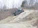 1992 Ford Bronco - An off-road vehicle navigates a challenging rocky terrain with an orange flag on top.