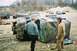 1992 Ford Bronco - Two men observe a mud-covered, overturned SUV at an outdoor event.