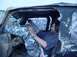 1992 Ford Bronco - Man sits in the driver's seat of a muddy vehicle, with another vehicle in the background.