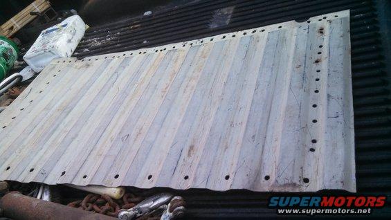 Corrugated metal sheet with holes along edges, lying in a truck bed with other items