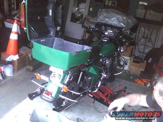 Green motorcycle rear view with open storage box