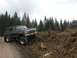 1979 Ford Bronco - This lifted Ford Bronco is navigating a rough, wooded terrain with a cloudy sky overhead.