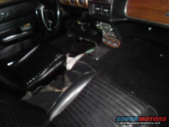Car interior showing black seats, dashboard, and steering wheel. Some items are on the floor