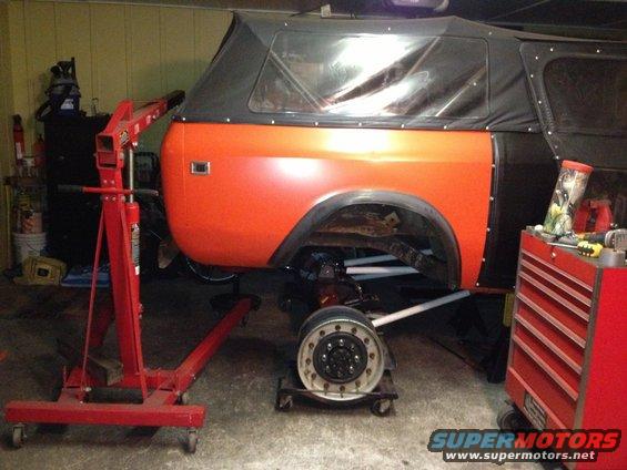 Orange International Harvester Scout II with black soft top, undergoing repairs, side view
