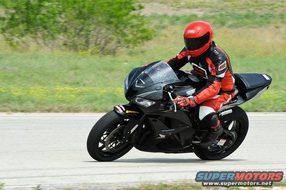 Black motorcycle with rider in red and black gear on a track