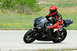 2001 Kawasaki KZ1000-A1 - A rider in full racing gear navigates a turn on a black sport motorcycle.