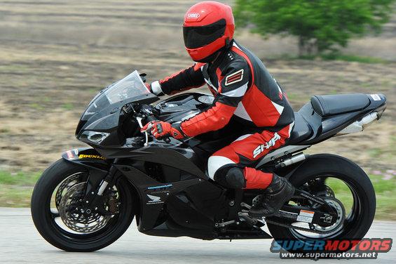 Rider in red and black leathers on a black sportbike, seen from the side