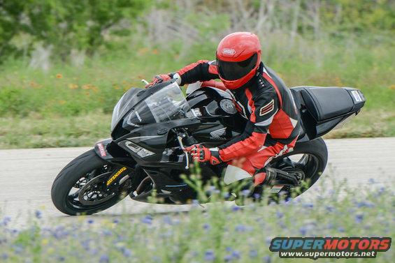 Black motorcycle leaning into a turn, rider in red and black suit