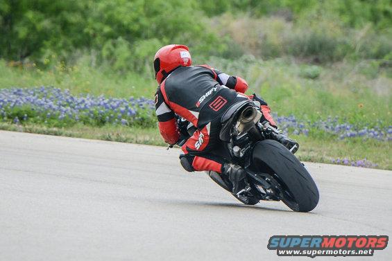 Motorcycle leaning into a turn, rider in red and black gear
