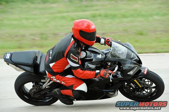 Rider in red and black gear on a black sportbike, leaning into a turn