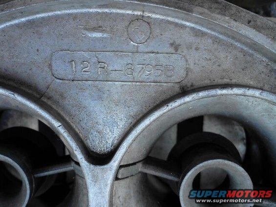 Close-up of a metal carburetor casting with part number 12R-8795B stamped into it