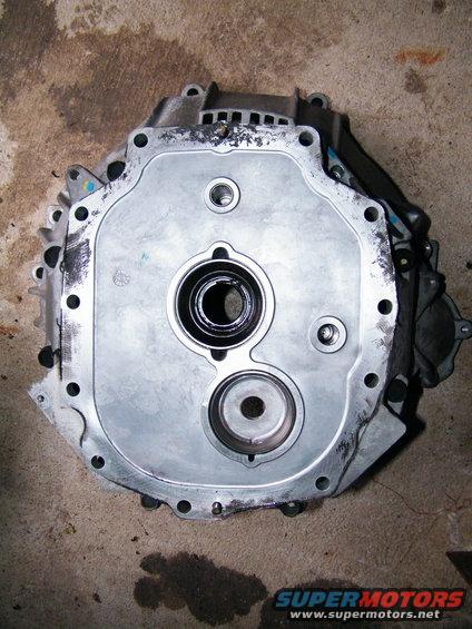 Close-up of a metal transmission component with circular openings and bolt holes