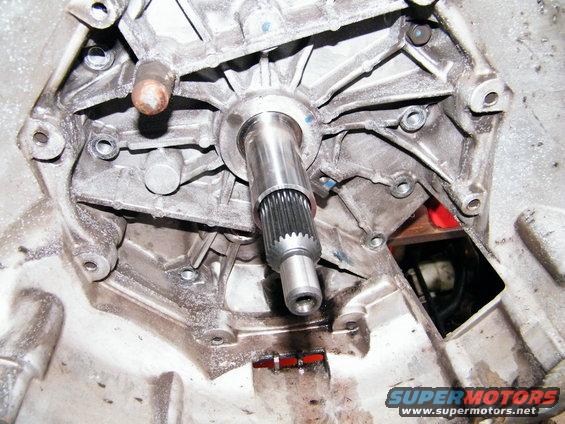 Transmission housing with splined shaft and mounting bolts. Watermark reads SUPERMOTORS.NET