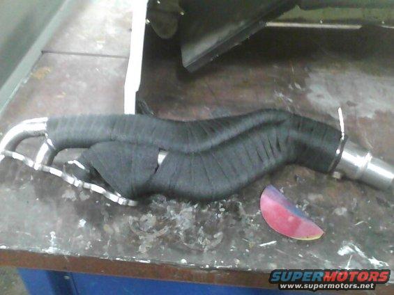 exhaust pipe wrapped in black heat tape, sitting on a workbench
