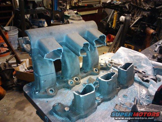 cut aluminum intake manifold with four ports, sitting on a workbench