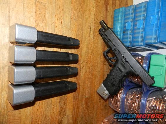 Four pistol magazines stacked, a Glock pistol, and boxes of ammunition