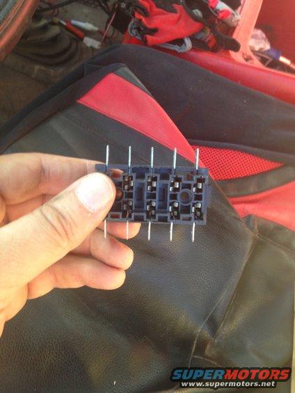 Hand holding a black plastic relay socket with metal pins