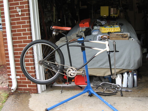 Bicycle frame in white and black on a blue stand, with a large rear wheel attached