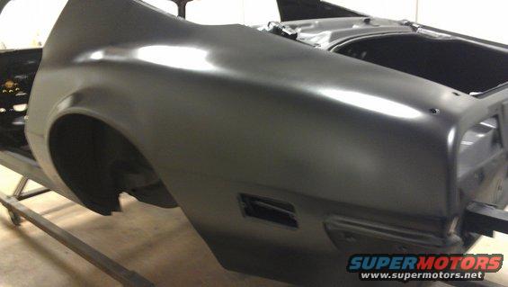 Black car body panel on a stand, showing rear quarter panel and trunk area