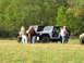 1979 Ford Bronco - Multiple Jeeps are gathered in a sunlit, grassy area with a wooded backdrop.