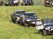 1979 Ford Bronco - A collection of modified off-road vehicles are gathered on a grassy incline, with a blue Toyota Tundra prominently featured.
